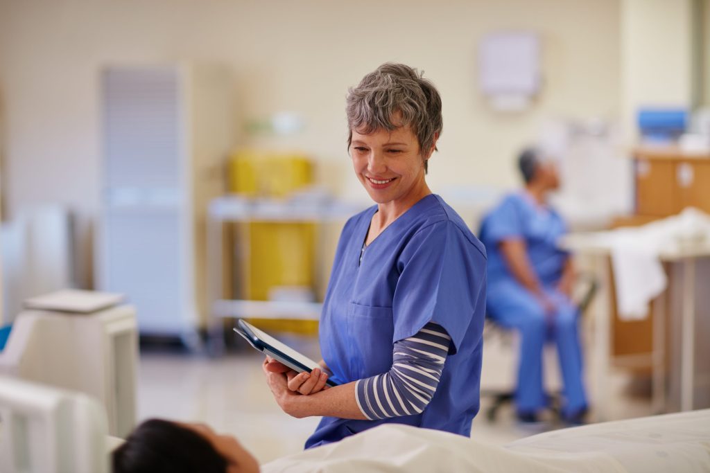 Knights Legal Services - A woman in scrubs standing in a hospital room holding a tablet.
